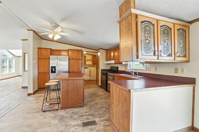6257 State Highway 70, Rock Creek, MN 55063 - kitchen featuring appliances with stainless steel finishes, washer and clothes dryer, a textured ceiling, vaulted ceiling, and a kitchen bar