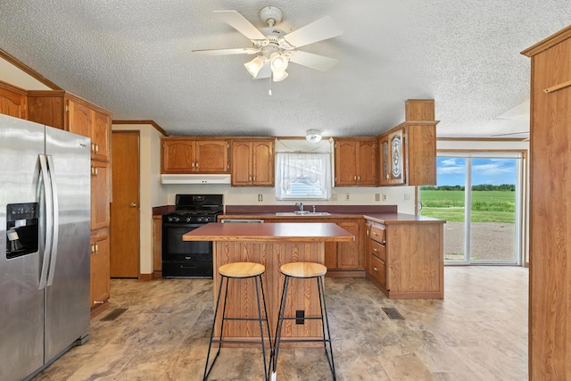 6257 State Highway 70, Rock Creek, MN 55063 - kitchen with stainless steel refrigerator with ice dispenser, black range with gas stovetop, a textured ceiling, a kitchen island, and healthy amount of natural light