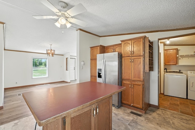 6257 State Highway 70, Rock Creek, MN 55063 - kitchen with washing machine and clothes dryer, stainless steel fridge, ornamental molding, brown cabinets, and a kitchen island