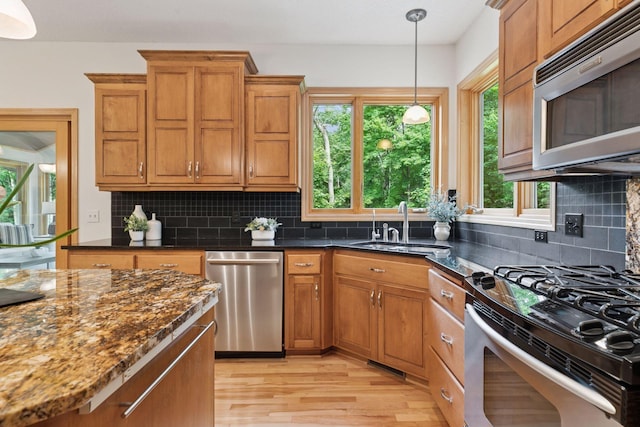 3027 135th Ave NE, Ham Lake, MN 55304 - kitchen with stainless steel appliances, light wood-type flooring, dark stone countertops, and brown cabinets