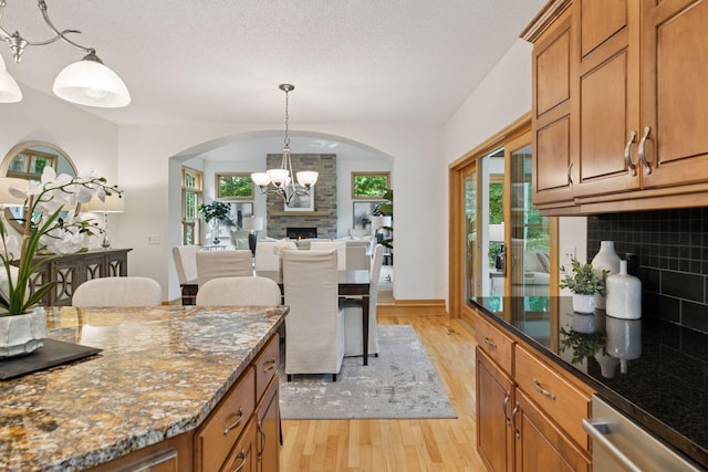 3027 135th Ave NE, Ham Lake, MN 55304 - kitchen with light wood-style flooring, a chandelier, stainless steel dishwasher, arched walkways, and brown cabinetry