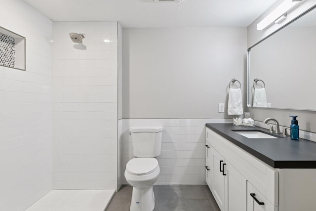 3027 135th Ave NE, Ham Lake, MN 55304 - bathroom featuring tiled shower, tile patterned floors, vanity, tile walls, and a wainscoted wall