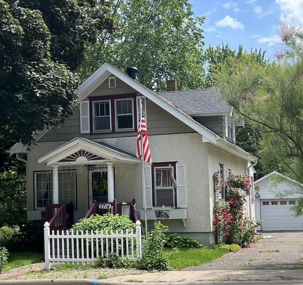 2714 17th Ave E, North Saint Paul, MN 55109 - view of front of home featuring an outdoor structure, a chimney, stucco siding, a garage, and driveway