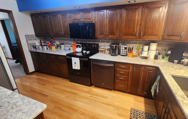511 4th St W, Jasper, MN 56144 - kitchen with black appliances, light wood finished floors, backsplash, and light stone countertops