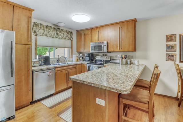 2744 32nd St S, Moorhead, MN 56560 - kitchen with appliances with stainless steel finishes, a peninsula, light wood-type flooring, light countertops, and a kitchen bar