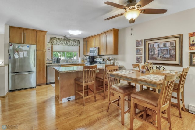 2744 32nd St S, Moorhead, MN 56560 - kitchen with stainless steel appliances, a peninsula, light wood-style flooring, ceiling fan, and light stone counters