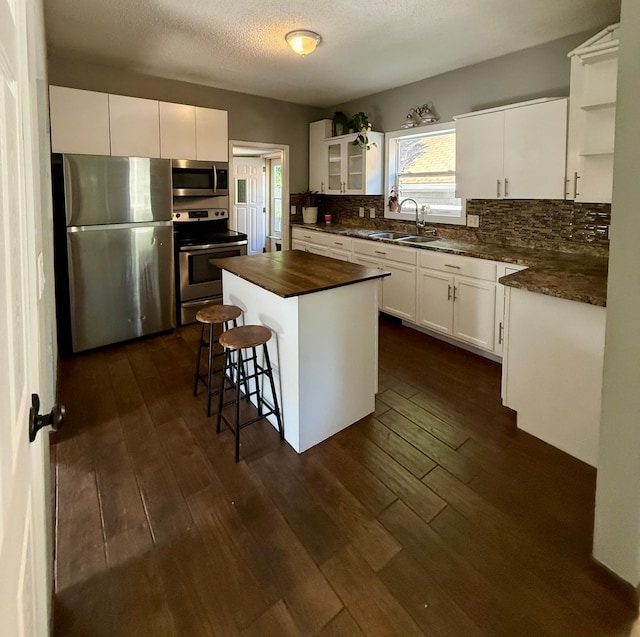 1212 Gorton Ave NW, Willmar, MN 56201 - kitchen featuring appliances with stainless steel finishes, decorative backsplash, dark wood-style flooring, white cabinetry, and a textured ceiling