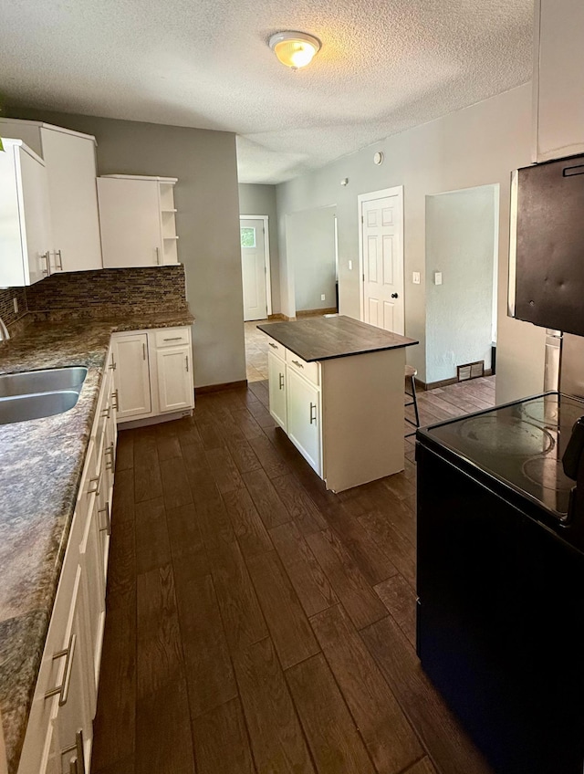 1212 Gorton Ave NW, Willmar, MN 56201 - kitchen featuring black / electric stove, dark countertops, a textured ceiling, open shelves, and dark wood finished floors