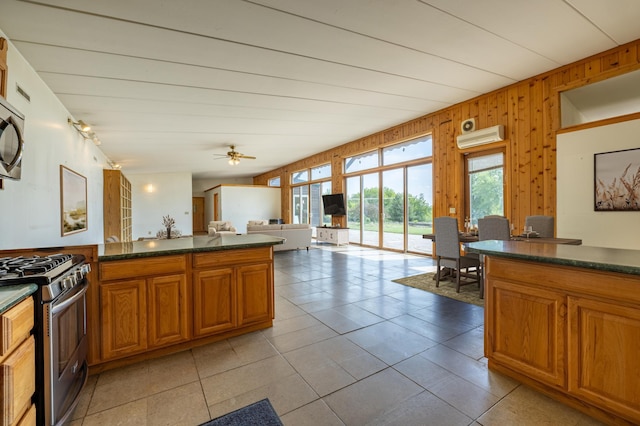 21555 699th St, Wabasha, MN 55981 - kitchen with appliances with stainless steel finishes, dark countertops, brown cabinetry, wood walls, and light tile patterned flooring