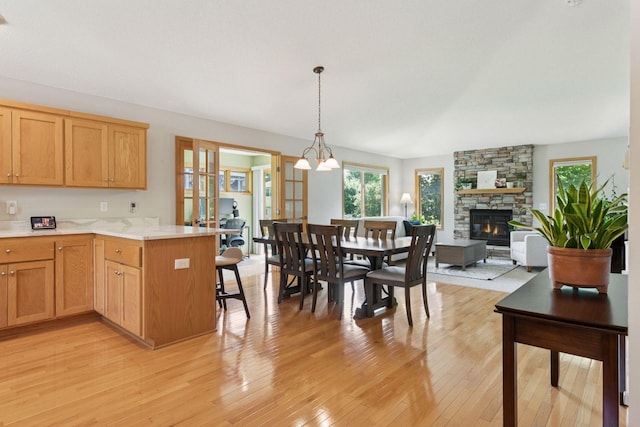 15450 Goodview Ave N, Hugo, MN 55038 - kitchen featuring light wood-type flooring, light countertops, a fireplace, a peninsula, and decorative light fixtures