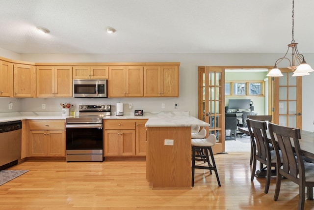 15450 Goodview Ave N, Hugo, MN 55038 - kitchen with appliances with stainless steel finishes, french doors, a kitchen bar, light wood-type flooring, and light countertops