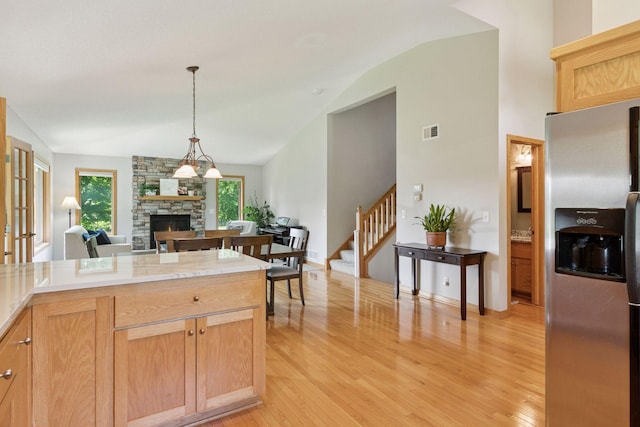 15450 Goodview Ave N, Hugo, MN 55038 - kitchen with stainless steel fridge with ice dispenser, a stone fireplace, lofted ceiling, light wood finished floors, and light countertops