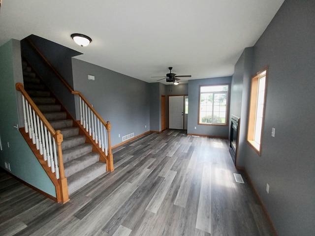 21196 Morgan Dr, Forest Lake, MN 55025 - unfurnished living room featuring wood finished floors, stairs, ceiling fan, and a glass covered fireplace