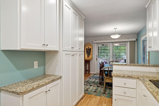 8447 Morgan Ln, Eden Prairie, MN 55347 - kitchen with light wood finished floors, white cabinets, light stone countertops, and a textured ceiling