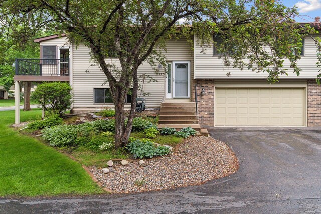 8447 Morgan Ln, Eden Prairie, MN 55347 - view of front facade with a garage, asphalt driveway, brick siding, and a balcony