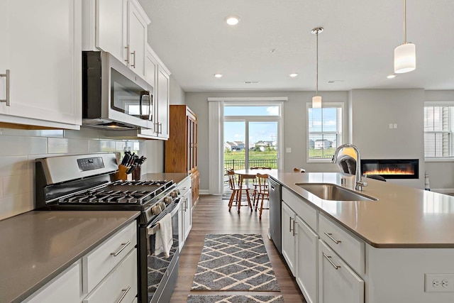 14145 Aberdeen Way, Rosemount, MN 55068 - kitchen featuring appliances with stainless steel finishes, dark wood finished floors, healthy amount of natural light, recessed lighting, and a glass covered fireplace