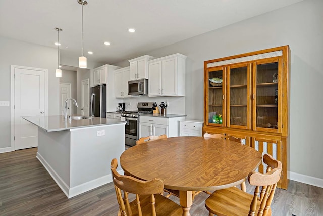 14145 Aberdeen Way, Rosemount, MN 55068 - kitchen featuring stainless steel appliances, a center island with sink, dark wood-style flooring, white cabinetry, and decorative light fixtures