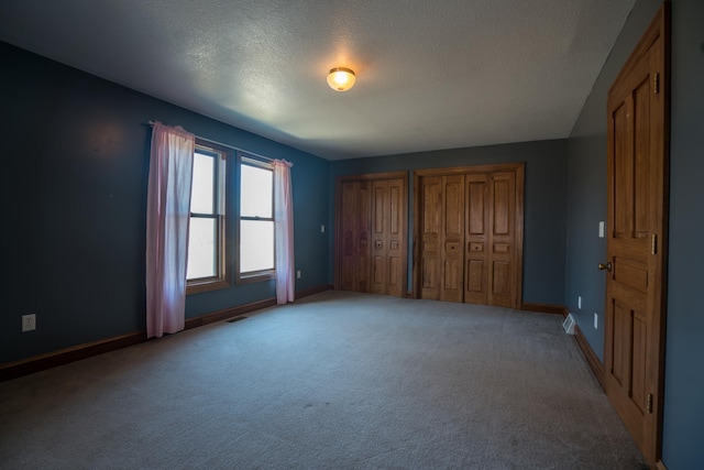 1757 325th Ave, West Sweden Twp, WI 54837 - unfurnished bedroom featuring multiple closets, light colored carpet, and a textured ceiling