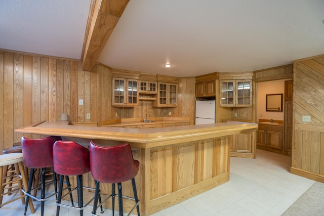 1757 325th Ave, West Sweden Twp, WI 54837 - kitchen featuring wooden walls, freestanding refrigerator, glass insert cabinets, a kitchen bar, and a peninsula