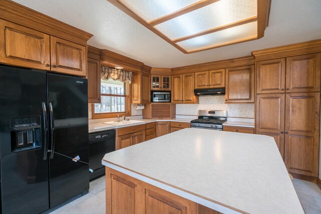 1757 325th Ave, West Sweden Twp, WI 54837 - kitchen featuring black appliances, under cabinet range hood, brown cabinets, light countertops, and a kitchen island
