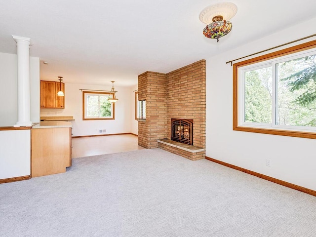 7651 86th St, Bloomington, MN 55438 - unfurnished living room featuring decorative columns, light colored carpet, and a brick fireplace