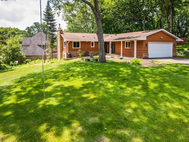 7651 86th St, Bloomington, MN 55438 - ranch-style home with a chimney, asphalt driveway, an attached garage, and view of wooded area