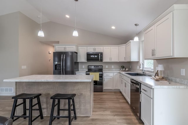 2216 Lake Ave, New Ulm, MN 56073 - kitchen featuring black appliances, vaulted ceiling, a center island, light wood-style flooring, and white cabinetry