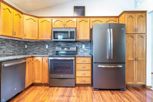 152 17th Ave W, West Fargo, ND 58078 - kitchen featuring appliances with stainless steel finishes, lofted ceiling, decorative backsplash, and light wood-type flooring