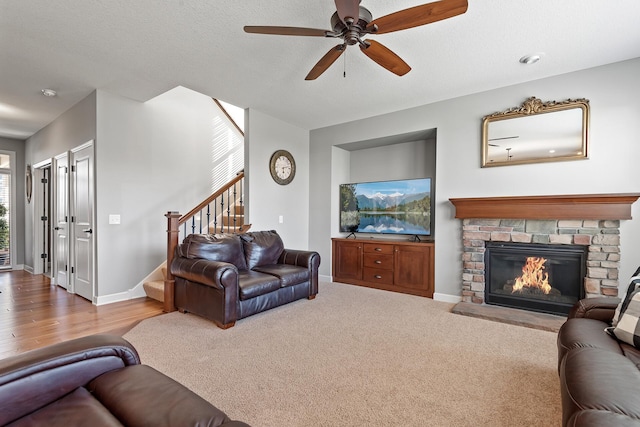9871 7th St N, Lake Elmo, MN 55042 - living area with stairway, a stone fireplace, a ceiling fan, and a textured ceiling