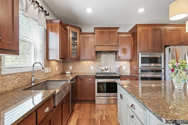 9871 7th St N, Lake Elmo, MN 55042 - kitchen with appliances with stainless steel finishes, light wood-type flooring, dark stone countertops, glass insert cabinets, and recessed lighting