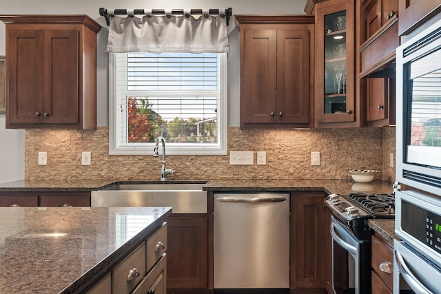 9871 7th St N, Lake Elmo, MN 55042 - kitchen with appliances with stainless steel finishes, glass insert cabinets, dark stone counters, and decorative backsplash