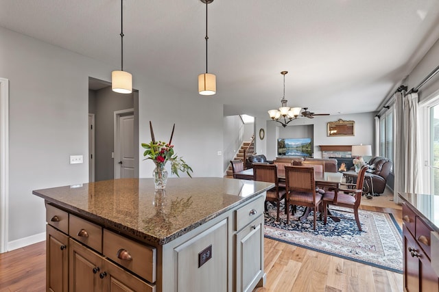 9871 7th St N, Lake Elmo, MN 55042 - kitchen featuring light wood-style floors, open floor plan, a center island, pendant lighting, and dark stone counters