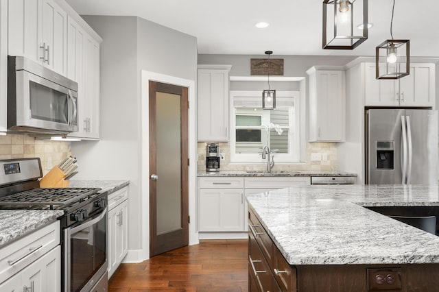 677 Sandstone Cir, Orono, MN 55356 - kitchen with appliances with stainless steel finishes, dark wood finished floors, white cabinetry, backsplash, and pendant lighting