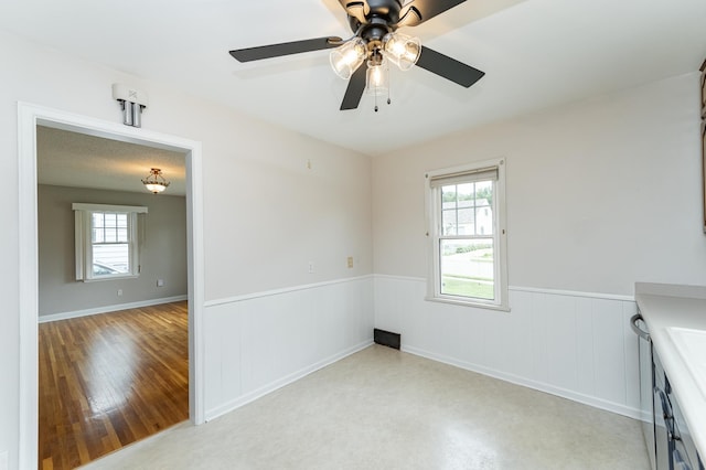 1007 12th Ave NE, Rochester, MN 55906 - spare room with plenty of natural light, a wainscoted wall, a ceiling fan, and light wood-style floors