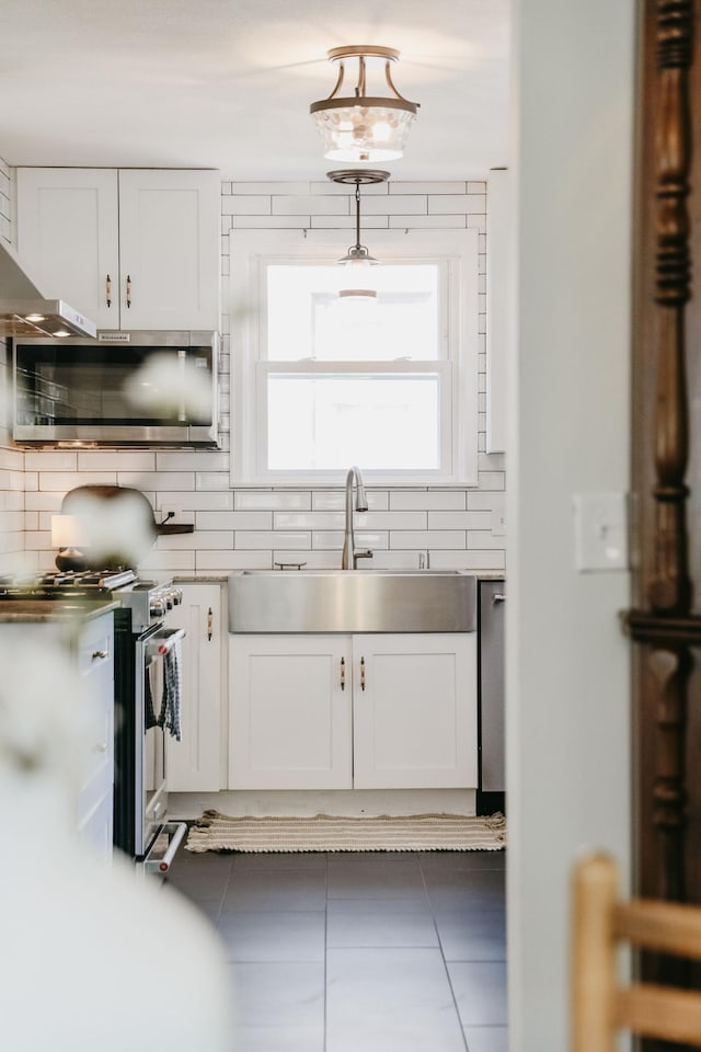 3615 33rd Ave S, Minneapolis, MN 55406 - kitchen featuring stainless steel appliances, decorative backsplash, tile patterned floors, white cabinets, and stainless steel counters