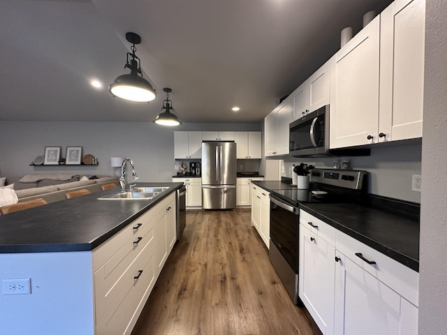 1817 Ridgewood Cir, Menomonie, WI 54751 - kitchen featuring appliances with stainless steel finishes, dark countertops, dark wood-style flooring, white cabinets, and hanging light fixtures