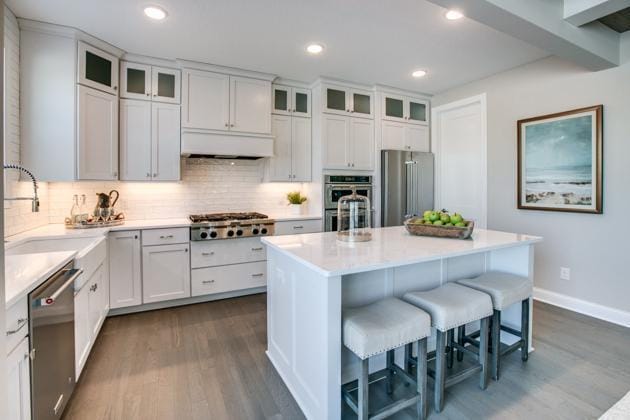 18210 102nd Pl N, Maple Grove, MN 55311 - kitchen featuring appliances with stainless steel finishes, dark wood-style floors, a breakfast bar, decorative backsplash, and recessed lighting