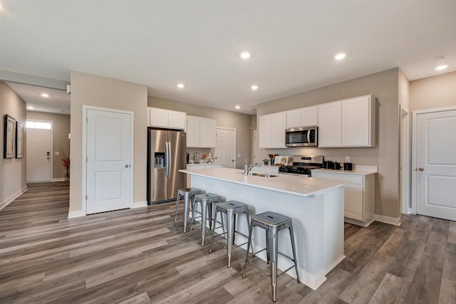 17021 Draper Way, Lakeville, MN 55044 - kitchen with stainless steel appliances, a breakfast bar, an island with sink, light wood finished floors, and white cabinetry
