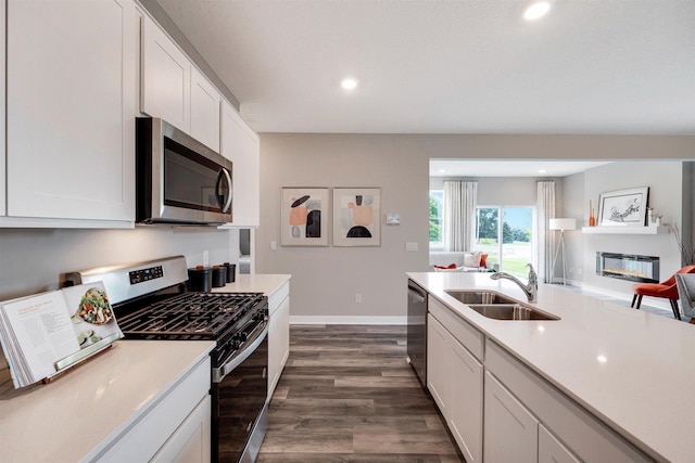 17021 Draper Way, Lakeville, MN 55044 - kitchen featuring stainless steel appliances, a glass covered fireplace, dark wood-style floors, light countertops, and recessed lighting