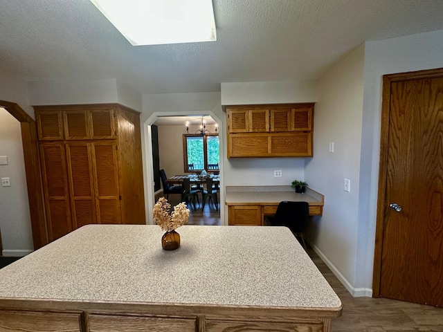 18224 Flanders St NE, East Bethel, MN 55092 - kitchen with brown cabinetry, light countertops, arched walkways, a center island, and wood finished floors