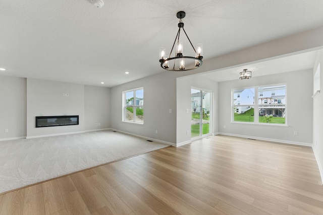 19391 Clearwater Loop, Farmington, MN 55024 - unfurnished living room with light wood-style flooring, a chandelier, a glass covered fireplace, and recessed lighting