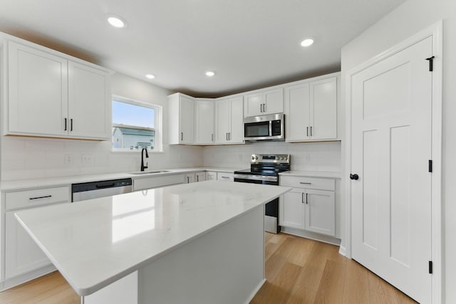 19391 Clearwater Loop, Farmington, MN 55024 - kitchen with stainless steel appliances, light wood-type flooring, white cabinets, decorative backsplash, and a kitchen island