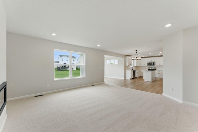 19391 Clearwater Loop, Farmington, MN 55024 - unfurnished living room featuring light carpet, a chandelier, and recessed lighting