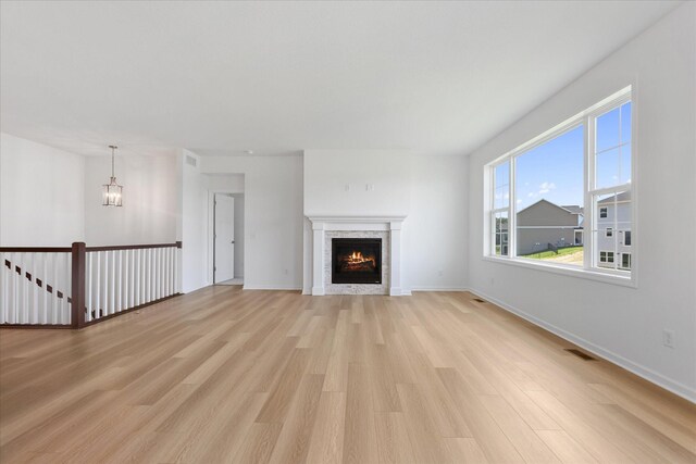 14990 144th Ave N, Dayton, MN 55327 - unfurnished living room featuring light wood-style flooring, a lit fireplace, and a chandelier