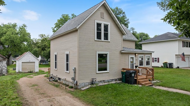 205 Main St, Marshall, MN 56258 - back of property with a yard, roof with shingles, driveway, and an outdoor structure