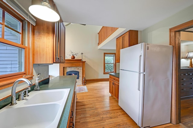 4623 Blaisdell Ave S, Minneapolis, MN 55419 - kitchen with freestanding refrigerator, a lit fireplace, light wood-type flooring, and brown cabinets