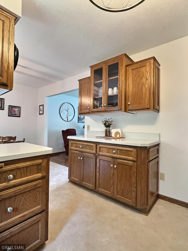 320 Ramey Rd, Maple Lake, MN 55358 - kitchen featuring light carpet, light countertops, glass insert cabinets, a desk, and a textured ceiling