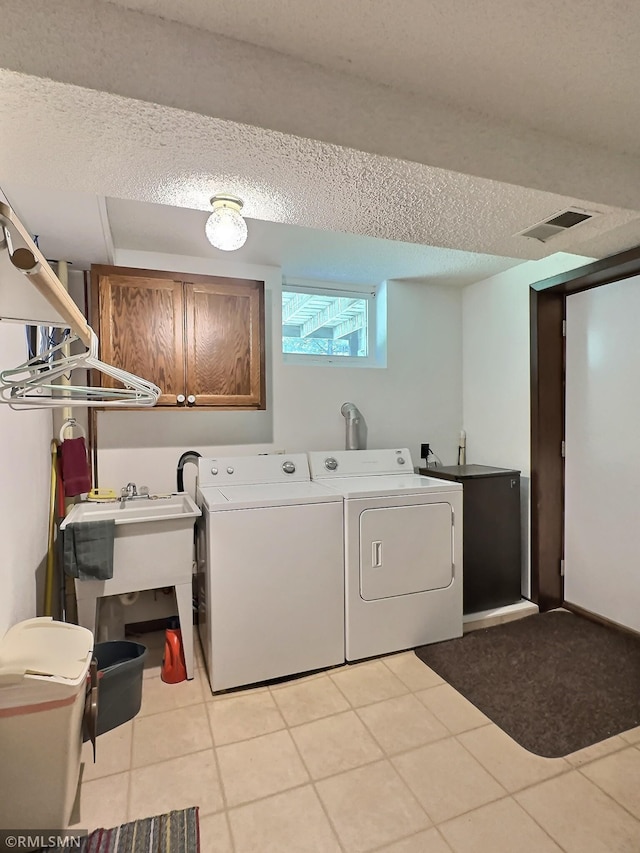 320 Ramey Rd, Maple Lake, MN 55358 - laundry area with cabinet space, separate washer and dryer, a textured ceiling, and light tile patterned flooring