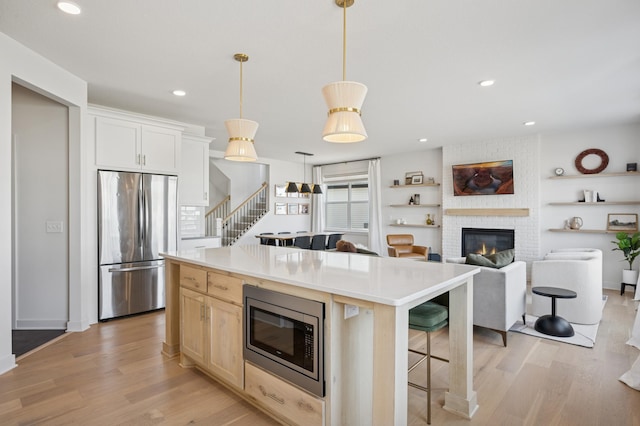 2348 Kester Ave NE, Saint Michael, MN 55376 - kitchen featuring stainless steel appliances, light wood-style floors, a fireplace, a kitchen island, and recessed lighting