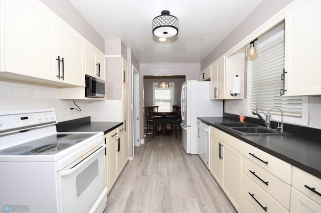 1253 3rd St N, Fargo, ND 58102 - kitchen featuring white appliances, decorative backsplash, dark countertops, and light wood finished floors